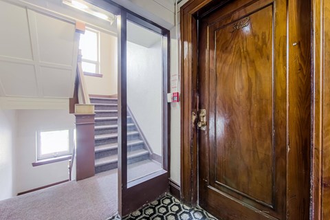 the entrance to a hallway with a wooden door and stairs